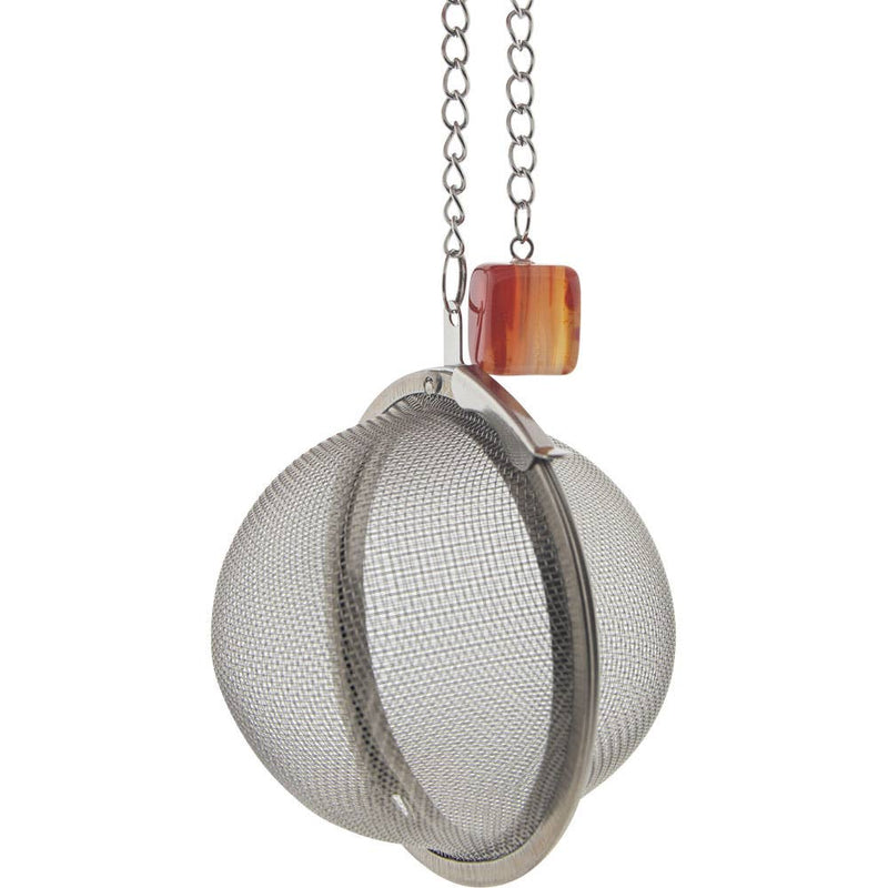 A stainless steel tea infuser ball with a carnelian charm hanging from a chain.