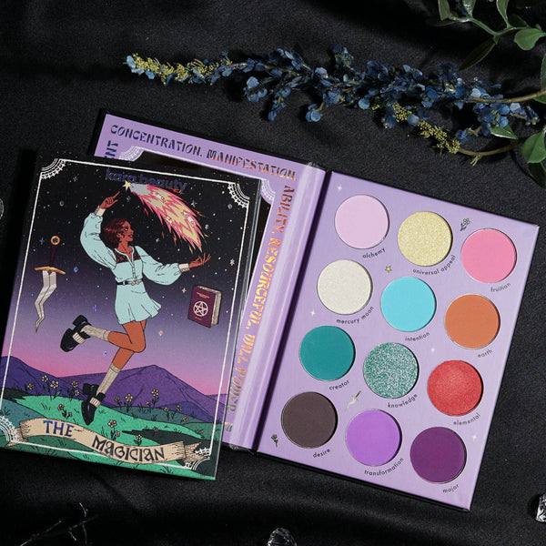 A colorful eyeshadow palette with various shades including mattes, shimmers, and glitters, with a graphic of 'The Magician' tarot card in the background.