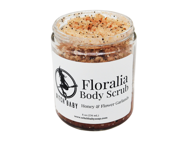 Sugar scrub with poppy seeds and earthy hue packaged in 8 oz glass jar with white label that reads: Floralia Body Scrub. Honey & Flower Garlands.