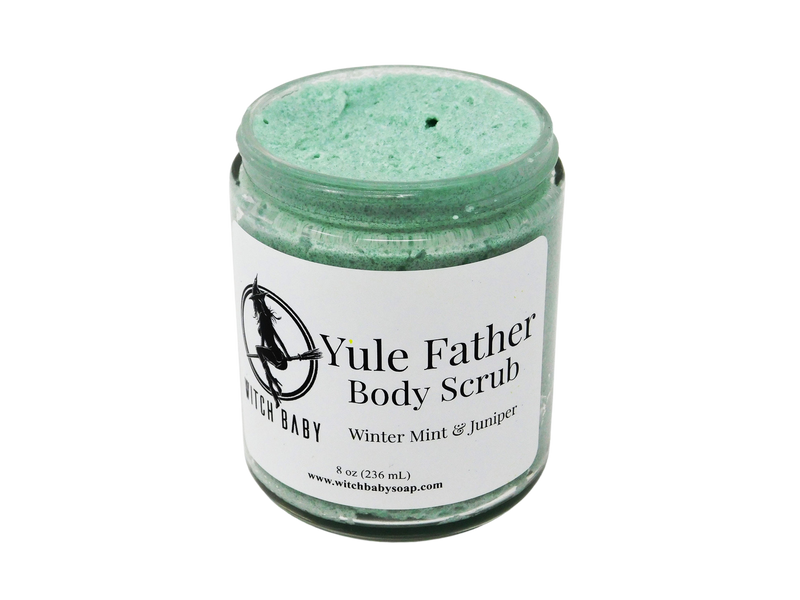Green holiday body scrub  pictured on a white background. Pictures a thick green moisturizing holiday themed scrub packaged in a glass jar with a white label that displays the witch baby logo and reads: yule father body scrub, winter mint & juniper. 8 oz (236 mL) www.witchbabysoap.com